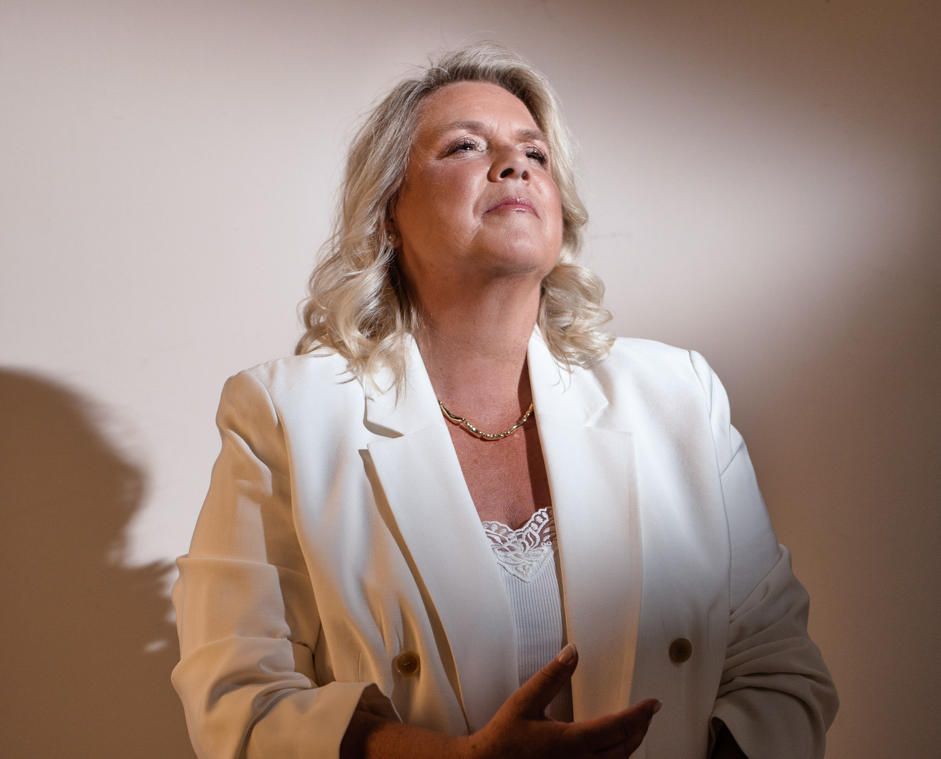Camilla Ma Ra standing in a cream suit, looking upward