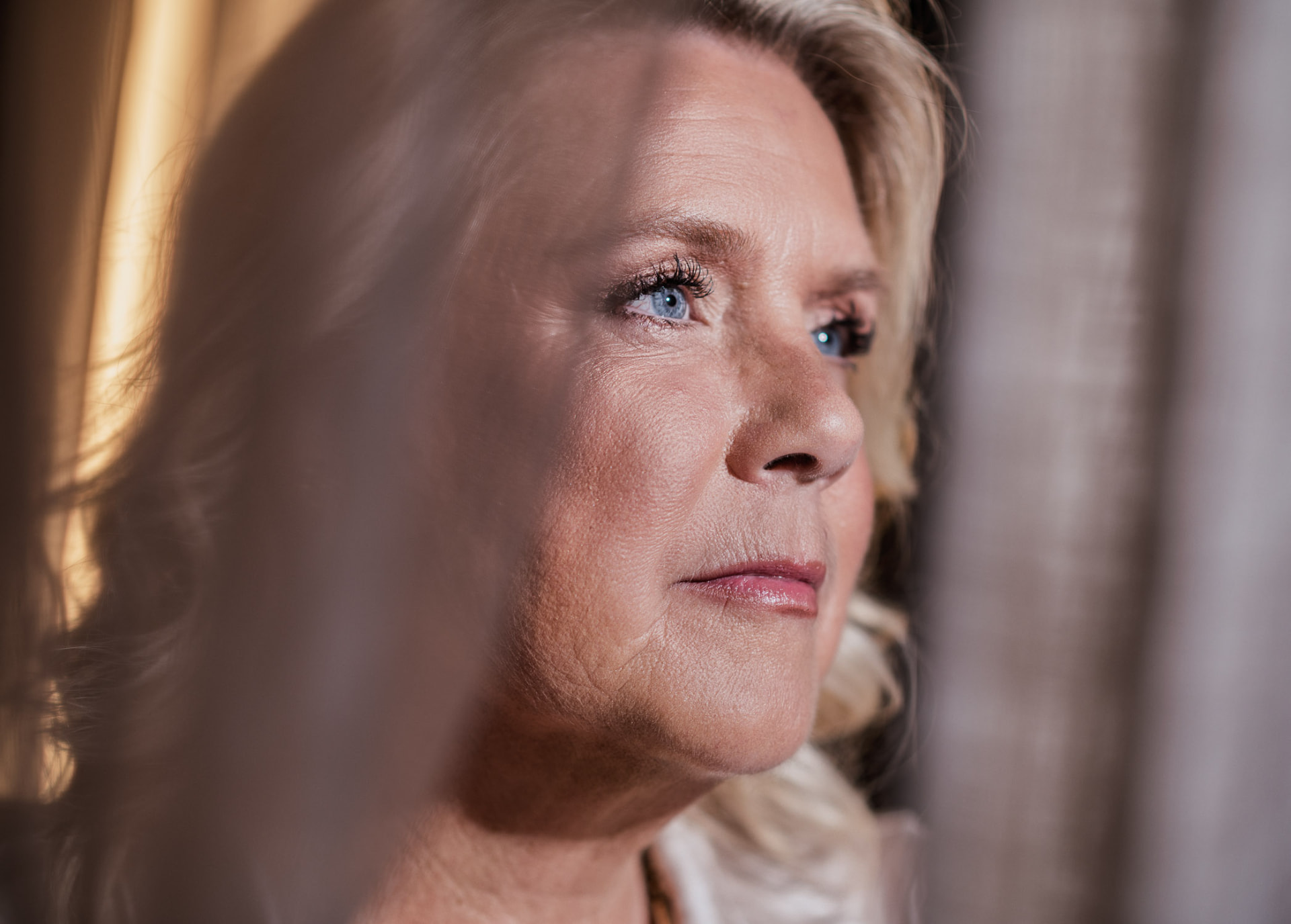 Camilla Ma Ra in a quiet, contemplative close-up beside sheer fabric